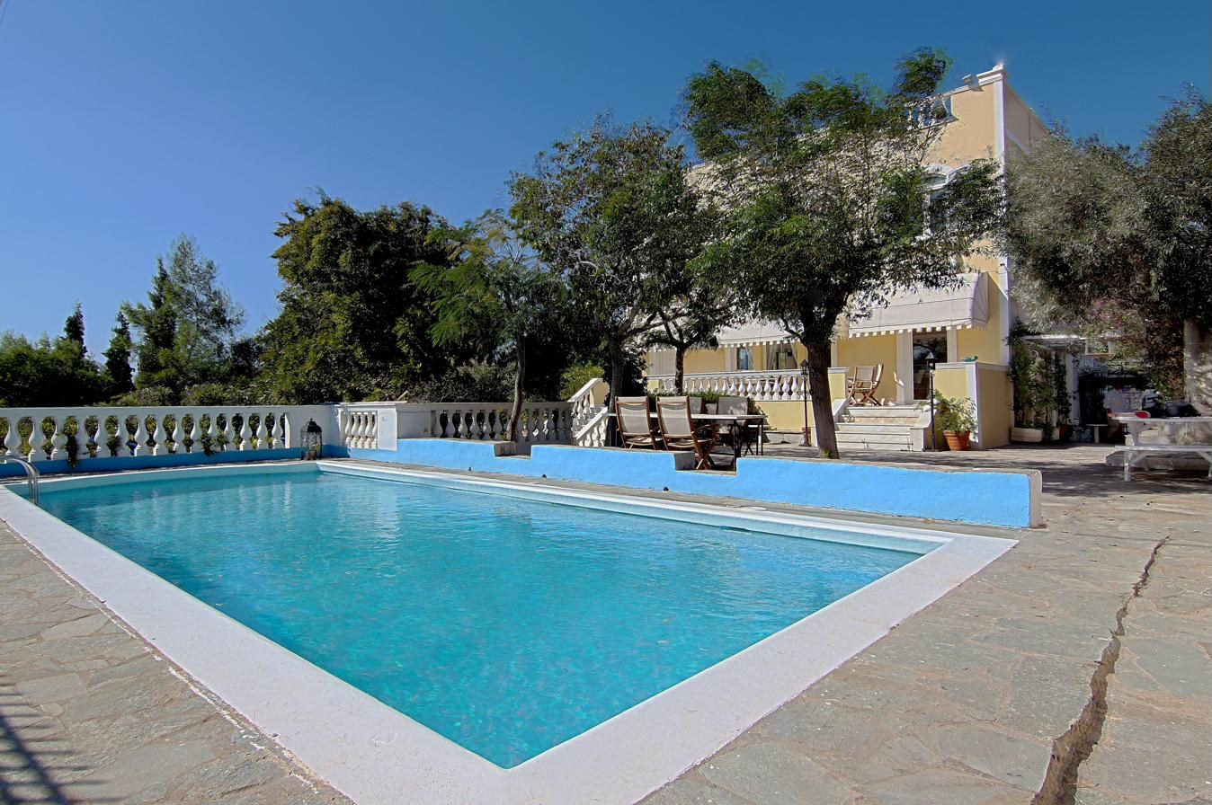 The private pool at Villa Emily, with the yellow villa and pine trees behind